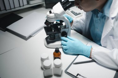 Laboratuvarda çalışan bilim adamı, bir tıp laboratuvarında araştırma yapan bilim adamları, ön planda bir araştırmacı bir mikroskop kullanıyor.,