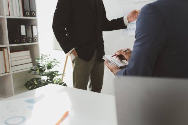 Toplantıda raporu açıklamak, toplantı odasındaki sorunları çözmek için işbirliği yapmak, ofisteki ekiple iş kurma konusunu tartışmak, masanın etrafında oturan karışık bir grup iş adamı..