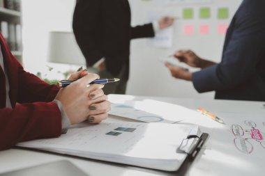 Toplantıda raporu açıklamak, toplantı odasındaki sorunları çözmek için işbirliği yapmak, ofisteki ekiple iş kurma konusunu tartışmak, masanın etrafında oturan karışık bir grup iş adamı..