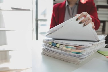 Ofiste yığınla belge düzenleniyor, çok sayıda önemli belge organize ediliyor, ofiste tek başına çalışırken diğer çalışanlar öğle yemeği molasında..