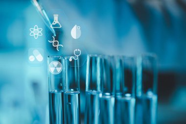 Araştırma laboratuarında teknisyen tüpü testi, kimyagerin elinde laboratuarda analiz makineleri bulunan bir raftan solüsyon örneği tüpü, pipetten tüpe sıvı damlatıyor..