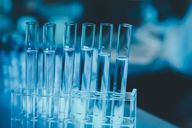 Araştırma laboratuarında teknisyen tüpü testi, kimyagerin elinde laboratuarda analiz makineleri bulunan bir raftan solüsyon örneği tüpü, pipetten tüpe sıvı damlatıyor..