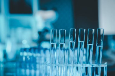 Araştırma laboratuarında teknisyen tüpü testi, kimyagerin elinde laboratuarda analiz makineleri bulunan bir raftan solüsyon örneği tüpü, pipetten tüpe sıvı damlatıyor..