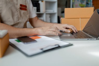 Bir çevrimiçi mağaza sahibi, çevrimiçi satış sitelerinden gelen siparişlere göre ürünleri paket kutularına koyar, özel kurye hizmeti yoluyla adreslere teslimat için ürünleri paketler. Ürün paketleme kavramı.