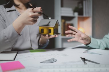 Mimarlar, ortakları ve çalışma sahasındaki model yapım ve plan araçları üzerinde çalışan proje için mühendis veya mimar toplantısının planlarını ve yapısını birlikte gözden geçiriyorlar.