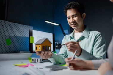 Mimarlar, ortakları ve çalışma sahasındaki model yapım ve plan araçları üzerinde çalışan proje için mühendis veya mimar toplantısının planlarını ve yapısını birlikte gözden geçiriyorlar.