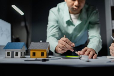 Mimarlar, ortakları ve çalışma sahasındaki model yapım ve plan araçları üzerinde çalışan proje için mühendis veya mimar toplantısının planlarını ve yapısını birlikte gözden geçiriyorlar.