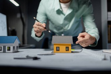 Mimarlar, ortakları ve çalışma sahasındaki model yapım ve plan araçları üzerinde çalışan proje için mühendis veya mimar toplantısının planlarını ve yapısını birlikte gözden geçiriyorlar.