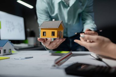 Mimarlar, ortakları ve çalışma sahasındaki model yapım ve plan araçları üzerinde çalışan proje için mühendis veya mimar toplantısının planlarını ve yapısını birlikte gözden geçiriyorlar.