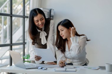 Ofiste dizüstü bilgisayar kullanan neşeli iş adamları, modern bir çalışma alanında birlikte çalışırken gülümseyen genç girişimciler, bir masada birlikte oturan iki genç iş adamı..