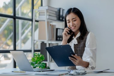 Bir girişimci, bir şirket müşterisiyle telefonda konuşuyor, ofiste güzel bir kadın, mutlu, iş kadını akıllı telefondan e-postaları kontrol ediyor, yönetici cep telefonu kullanıyor., 