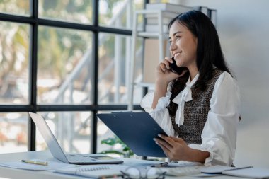 Bir girişimci, bir şirket müşterisiyle telefonda konuşuyor, ofiste güzel bir kadın, mutlu, iş kadını akıllı telefondan e-postaları kontrol ediyor, yönetici cep telefonu kullanıyor., 