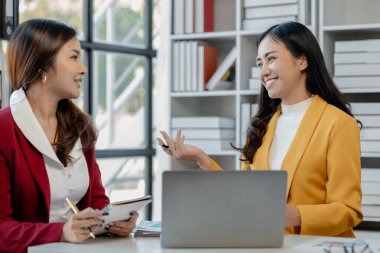 Ofiste dizüstü bilgisayar kullanan neşeli iş adamları, modern bir çalışma alanında birlikte çalışırken gülümseyen genç girişimciler, bir masada birlikte oturan iki genç iş adamı..