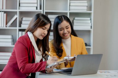 Ofiste dizüstü bilgisayar kullanan neşeli iş adamları, modern bir çalışma alanında birlikte çalışırken gülümseyen genç girişimciler, bir masada birlikte oturan iki genç iş adamı..