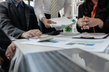 Çalışanlardan oluşan bir grup, yaklaşan bir etkinliğin detaylarını, toplantı durumunu yakından inceliyor. İş adamları ve kadınlar, şeffaf bir konferans odasında gergin bir toplantı yapıyorlar..