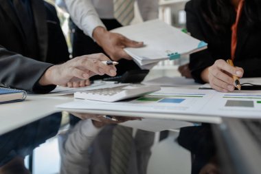 Çalışanlardan oluşan bir grup, yaklaşan bir etkinliğin detaylarını, toplantı durumunu yakından inceliyor. İş adamları ve kadınlar, şeffaf bir konferans odasında gergin bir toplantı yapıyorlar..