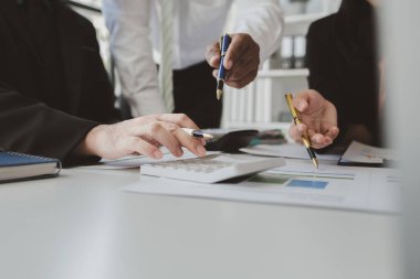 Çalışanlardan oluşan bir grup, yaklaşan bir etkinliğin detaylarını, toplantı durumunu yakından inceliyor. İş adamları ve kadınlar, şeffaf bir konferans odasında gergin bir toplantı yapıyorlar..