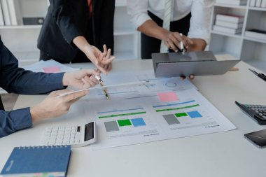 Çalışanlardan oluşan bir grup, yaklaşan bir etkinliğin detaylarını, toplantı durumunu yakından inceliyor. İş adamları ve kadınlar, şeffaf bir konferans odasında gergin bir toplantı yapıyorlar..