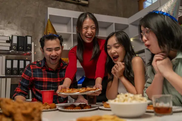 Happy diverse team people talking laughing eating pizza in office, Group of business people drinking at party in office, Colleagues eat together at a party and there is a lot of food on the table.