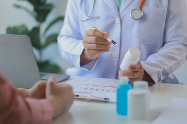 Doktor, hastanın alması gereken ilaçların detaylarını açıklarken, bir hasta ilaçların yan etkileri ile ilgili olarak doktoru görmeye gelir..