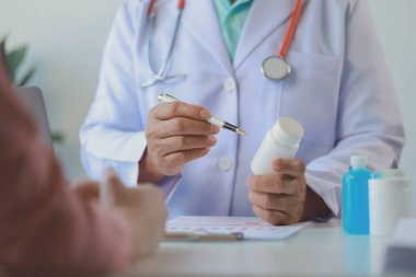 Doktor, hastanın alması gereken ilaçların detaylarını açıklarken, bir hasta ilaçların yan etkileri ile ilgili olarak doktoru görmeye gelir..