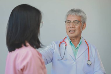 Doktor ve hasta geçmiş tıbbi geçmişi tartışıyor ve ayrıca gelecek tedavi planlarını tartışıyorlar. Hasta, hastayla ilgilenen doktorun ofisinde oturuyor..