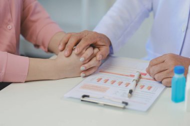 Doktor ve hasta geçmiş tıbbi geçmişi tartışıyor ve ayrıca gelecek tedavi planlarını tartışıyorlar. Hasta, hastayla ilgilenen doktorun ofisinde oturuyor..