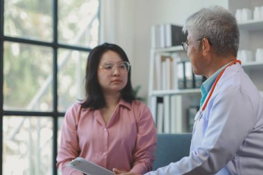 Doktor ve hasta geçmiş tıbbi geçmişi tartışıyor ve ayrıca gelecek tedavi planlarını tartışıyorlar. Hasta, hastayla ilgilenen doktorun ofisinde oturuyor..