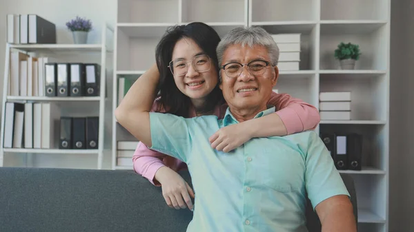 A father and daughter sat in the living room happily spending time together after not seeing each other for a while, A warm family is in the house, Elderly father and teenage daughter