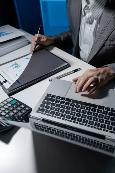 A young businessman is using a laptop to search for important information on business competitors, A laptop was used to access important documents by one employee.