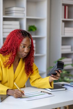 Şirketimizde özel bir ofiste oturan güzel bir Afrikalı iş kadını bir toplantıya hazırlanmak için bilgi arıyor masasında oturuyor ve farklı şeyler yapıyor..