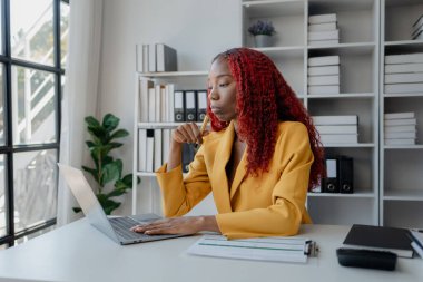 Şirketimizde özel bir ofiste oturan güzel bir Afrikalı iş kadını bir toplantıya hazırlanmak için bilgi arıyor masasında oturuyor ve farklı şeyler yapıyor..
