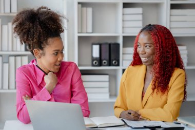 İki başarılı Afrikalı iş kadını gündüzleri şirkette birlikte iş yapma girişimlerini tartışıyorlar. Kadın Afrikalı işçiler ofiste bir proje hakkında konuşuyorlar..