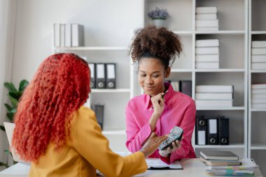 İki başarılı Afrikalı iş kadını gündüzleri şirkette birlikte iş yapma girişimlerini tartışıyorlar. Kadın Afrikalı işçiler ofiste bir proje hakkında konuşuyorlar..