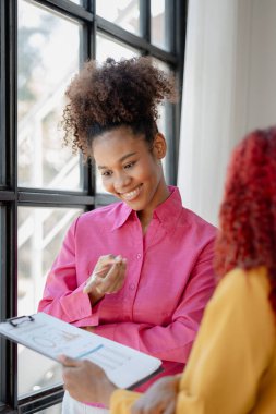 İki başarılı Afrikalı iş kadını gündüzleri şirkette birlikte iş yapma girişimlerini tartışıyorlar. Kadın Afrikalı işçiler ofiste bir proje hakkında konuşuyorlar..