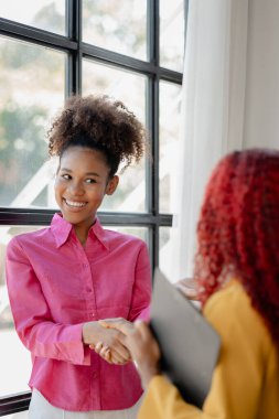 İki güzel Afrikalı kadın ofiste tokalaşırken önemli işler başarıyla tartışıldı. Güzel başarılı Afrikalı iş kadınları iş zaferi nedeniyle el ele tutuşuyorlar..