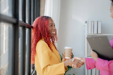 İki güzel Afrikalı kadın ofiste tokalaşırken önemli işler başarıyla tartışıldı. Güzel başarılı Afrikalı iş kadınları iş zaferi nedeniyle el ele tutuşuyorlar..