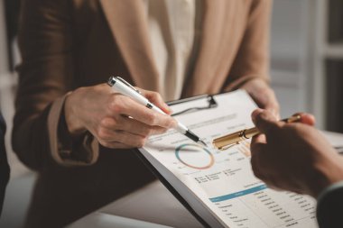 Bir grup iş adamı bir kapitaliste sunulacak önemli belgeleri tartışıyor, meslektaşlar birbirleriyle bilgi alışverişinde bulunuyor, toplantı odasında bilgi paylaşımı yapıyorlar.