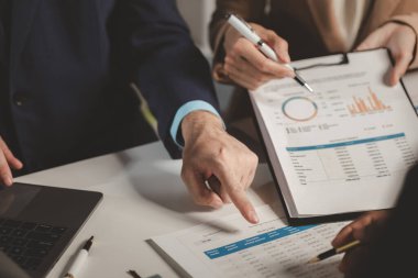 Bir grup iş adamı bir kapitaliste sunulacak önemli belgeleri tartışıyor, meslektaşlar birbirleriyle bilgi alışverişinde bulunuyor, toplantı odasında bilgi paylaşımı yapıyorlar.