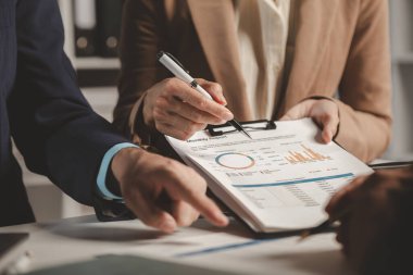 Bir grup iş adamı bir kapitaliste sunulacak önemli belgeleri tartışıyor, meslektaşlar birbirleriyle bilgi alışverişinde bulunuyor, toplantı odasında bilgi paylaşımı yapıyorlar.