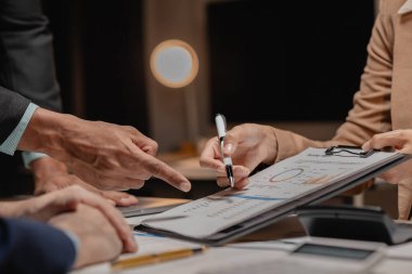 Bir grup iş adamı bir kapitaliste sunulacak önemli belgeleri tartışıyor, meslektaşlar birbirleriyle bilgi alışverişinde bulunuyor, toplantı odasında bilgi paylaşımı yapıyorlar.