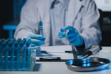 Bir bilim adamı deney için bilimsel ekipmanlarla dolu bir laboratuvar olan karnesine bir deneyin sonuçlarını yazıyor..