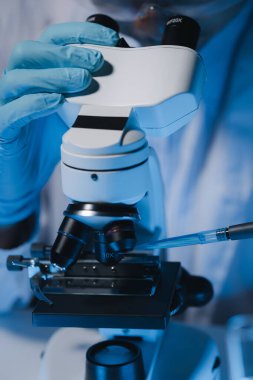 Bir bilim adamı mikrobiyoloji alanında mikroskop kullanarak örnekler üzerinde çalışıyor. Mikroskoplar kemoterapi araştırmaları için araştırmacılar tarafından kullanılıyor..