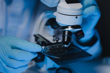 Bir bilim adamı mikrobiyoloji alanında mikroskop kullanarak örnekler üzerinde çalışıyor. Mikroskoplar kemoterapi araştırmaları için araştırmacılar tarafından kullanılıyor..