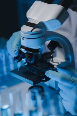 Bir bilim adamı mikrobiyoloji alanında mikroskop kullanarak örnekler üzerinde çalışıyor. Mikroskoplar kemoterapi araştırmaları için araştırmacılar tarafından kullanılıyor..