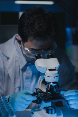 Bir bilim adamı mikrobiyoloji alanında mikroskop kullanarak örnekler üzerinde çalışıyor. Mikroskoplar kemoterapi araştırmaları için araştırmacılar tarafından kullanılıyor..