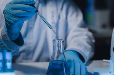 Bir araştırmacı deney tüpünde bulunan sıvıyı dikkatle inceliyor çünkü bu önemli bir araştırma alanıdır. Bir bilim adamı sıvılar üzerinde bilimsel bir deney yapmak için bir araç kullanıyor..