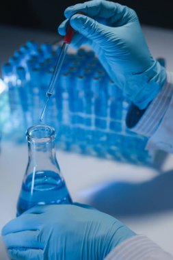 Bir araştırmacı deney tüpünde bulunan sıvıyı dikkatle inceliyor çünkü bu önemli bir araştırma alanıdır. Bir bilim adamı sıvılar üzerinde bilimsel bir deney yapmak için bir araç kullanıyor..