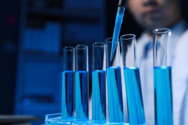 Bir kimyager, laboratuvarında çeşitli bilimsel ekipmanlar kullanarak yeni keşfedilen bir kimyasalı test ediyor..