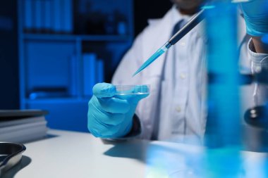 Bir kimyager, laboratuvarında çeşitli bilimsel ekipmanlar kullanarak yeni keşfedilen bir kimyasalı test ediyor..